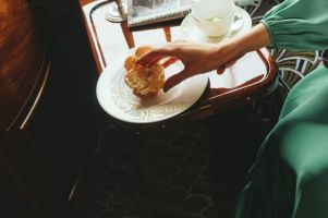 Close-up of a hand reaching for a brioche bun on a gold-detailed plate in a train cabin